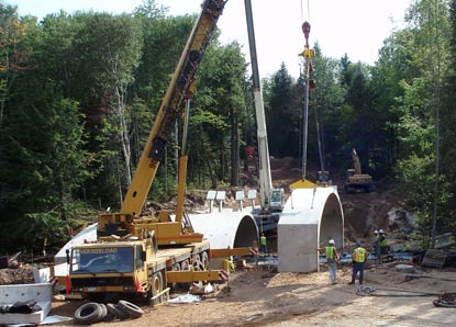 Cranes place a section of con-span for the new Hurricane River Bridge on H-58.