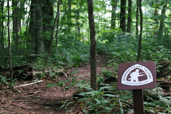 An Overmountain Victory National Historic Trail marker is to the right of a dirt path.