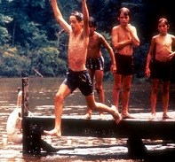 Young camper jumping off a dock into the lake