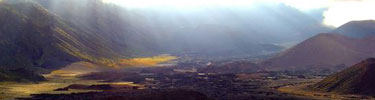 Sunbeams illuminate the clouds and the summit crater valley.