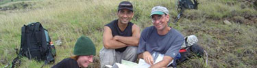 Hikers take a break all a grassy trail to plan the next phase of their backpack trip.