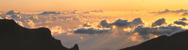 The clouds add color to the golden mountaintop sunrise.
