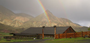 Image of Cant Ranch barn and a rainbow over Sheep Rock.