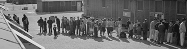 Waiting in line for a meal at a mess hall. Photo by Ansel Adams.