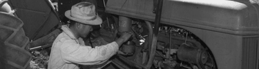 Mechanic Henry Hanawa repairs tractor engine. Photo by Ansel Adams.