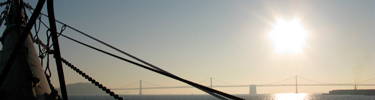 A closeup of BALCLUTHA'S bowsprint with the SF Oakland Bay Bridge in the distant background.