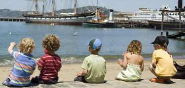 Young children on the beach looking at Hyde Street Pier.