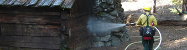 Firefighter hoses down cabin during a prescribed burn.