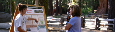 Fire Information Officer points to a bulletin board while talking to a visitor.