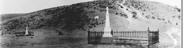 historic photo circa 1914: two fenced grave areas with tall grave markers