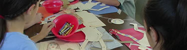 children sitting around a table cutting, pasting, and coloring