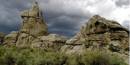 View of eroded granite spire with storm clouds in the background.