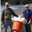 two people holding large orange basket; beach in background