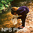 Female student standing in a stream inspecting the contents of a dip net