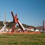 Massive sculpture rising with the Golden Gate Bridge in the distance.