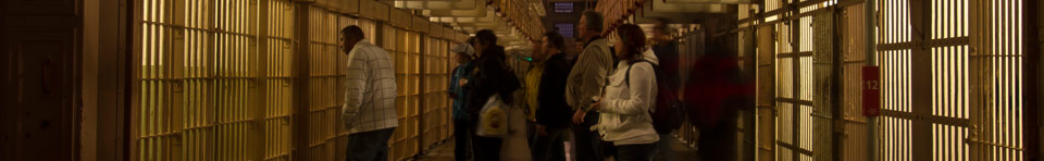 Visitor during the evening tour of Alcatraz gaze into the many cells that line up the corridor known as 