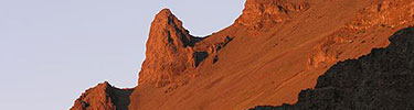 A volcanic dyke is made brilliant red in the evening sun.