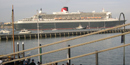 The Queen Mary 2, the largest ocean liner in the world, passing by the park with many smaller boats surrounding her. The Queen Mary 2, the largest ocean liner in the world, passing by the park with many smaller boats surrounding her.