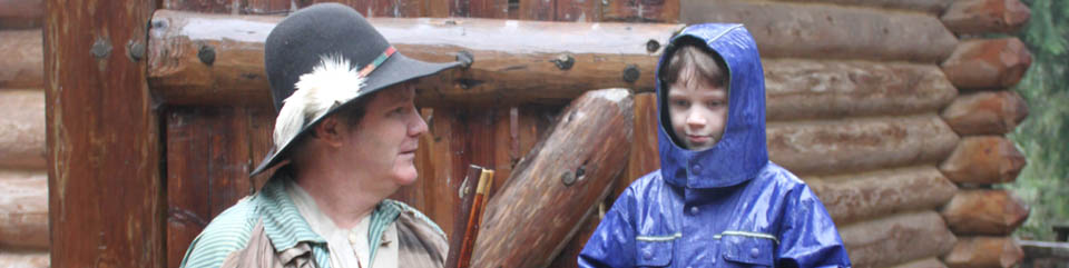 A young visitor talks with a ranger at the front gate of Fort Clatsop