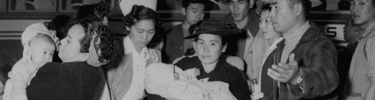 A baby with measles and mother are accompanied to the Manzanar hospital. Photo by Clem Albers.