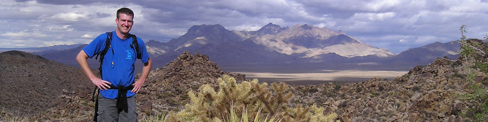 Hiker standing on mountiantop overlooking wide desert valley
