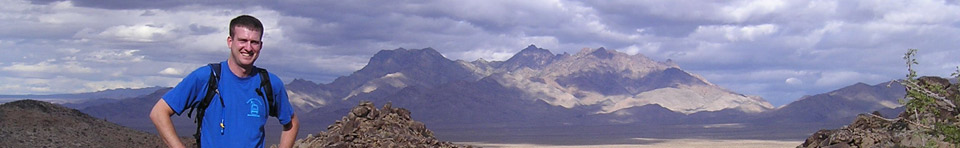Hiker standing on mountiantop overlooking wide desert valley