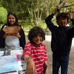 Photo of three kids holding a piece of redwood, a banana slug, and deer antlers