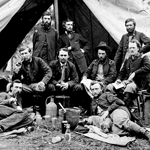 Civil War officers lounge in front of a tent.