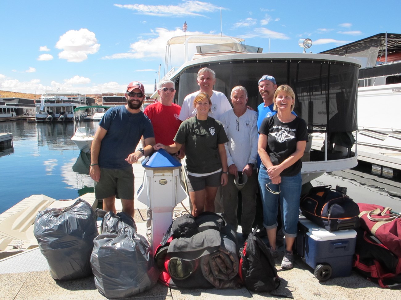 Group of volunteers assembled in front of True GRIT houseboat at dock
