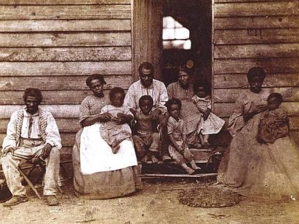 Slave family seated in front of their house