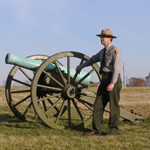 A ranger stands next to a cannon at Malvern Hill battlefield.