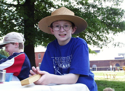 A young boy wears the ranger hat at a picnic table with games.