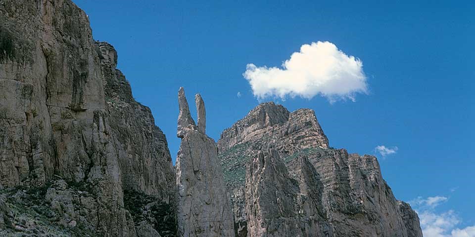 A rock spire in a high-walled river canyon looks like two rabbit ears.