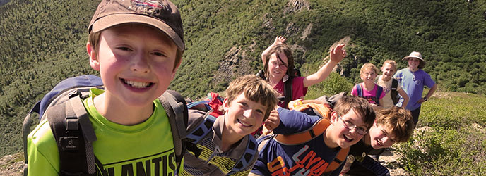 A group of kids smiling as they hike up a hill A group of kids smiling as they hike up a hill