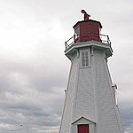 White lighthouse with red accents against a cloudy sky