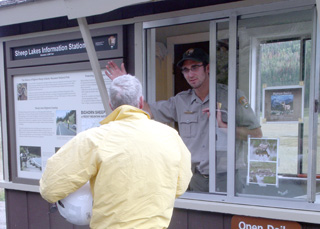 Photo of a park ranger assisting a visitor at Sheep Lakes Information Station. 