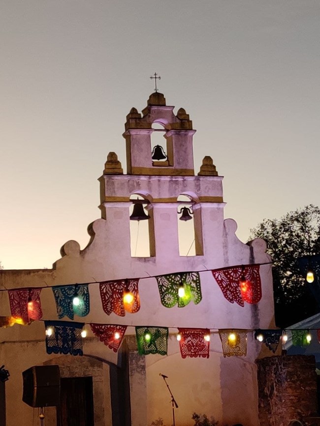 Mission San Juan at night with festive banner.