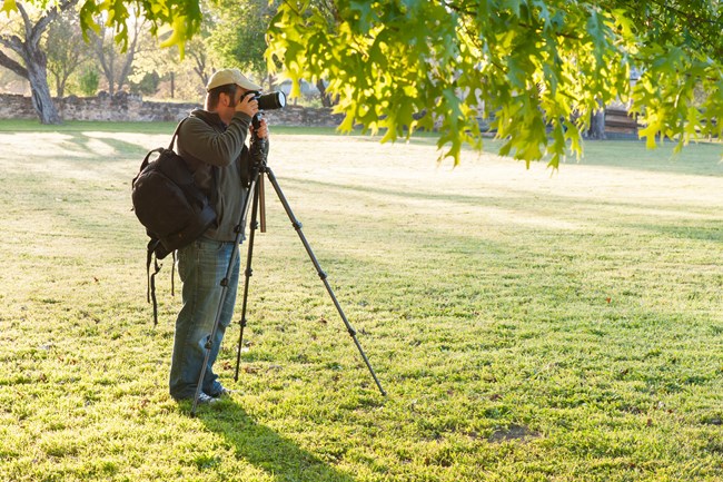 Visitor uses a tall tripod and camera to take photos at the park.