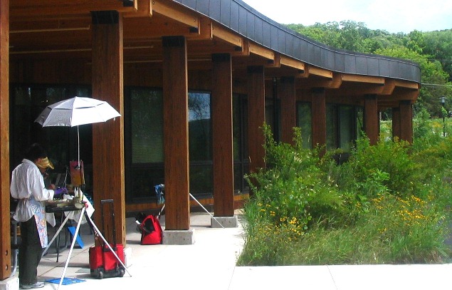 In the summer, an artisit paints the native plant landscape outside and adjacent to the St. Croix River Visitor Center. NPS Photo 