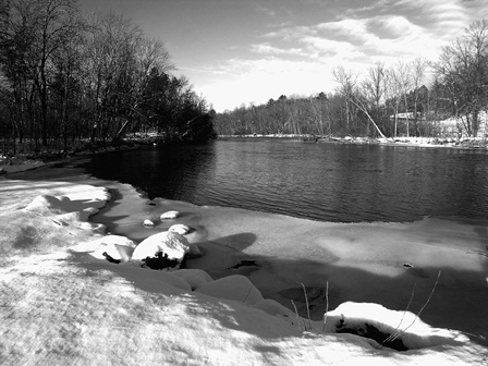The open waters of the Namekagon River flow around a bend and past a snow covered shoreline.