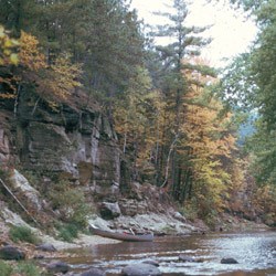 Wooded cliffs by a river in fall.