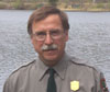 Man in National Park Service uniform standing in front of the river