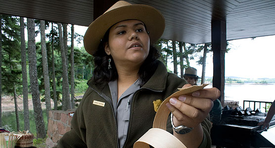 A park ranger holds a strip of bark in a basket-making demonstration.