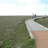 Two people on a boardwalk in a treeless open prairie in Kansas