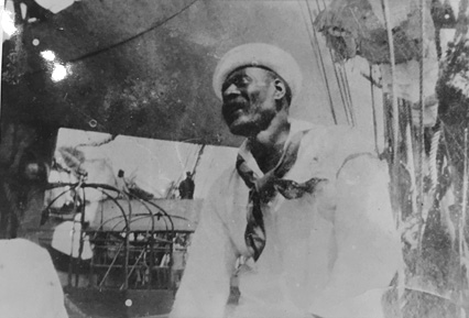 Sailor wearing traditional hat and scarf on the deck of a sailing ship