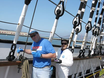 Two volunteers on the BALCLUTHA painting the ship railing.