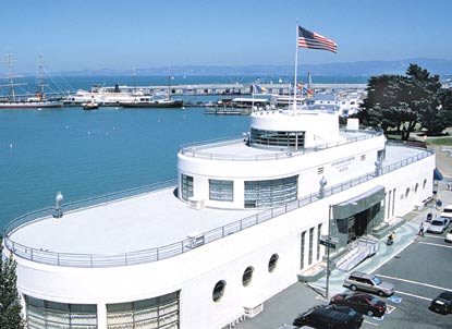 The Aquatic Park Bathhouse building with Hyde Street Pier and the historic ships in the background.