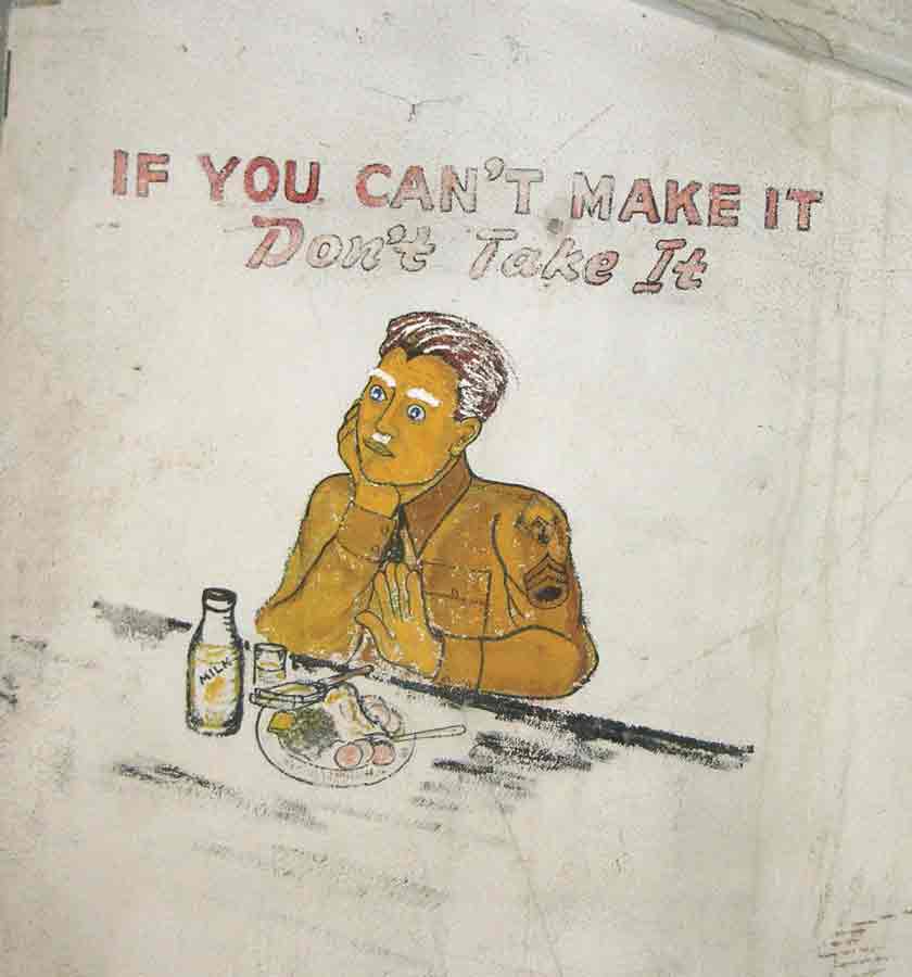 Mural painted on a plaster wall depicing a solider in a World War II uniform eating meal.