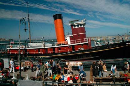 The tugboat HERCULES moored at Hyde Street Pier with people walking along the pier.