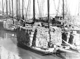 Scow schooner with a huge load of hay bales stacked high on the deck.